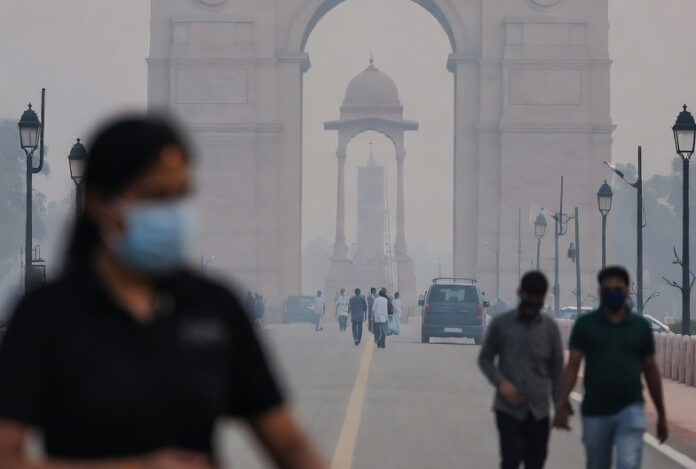 Masked commuters walk through thick haze near India Gate as AQI crosses 300