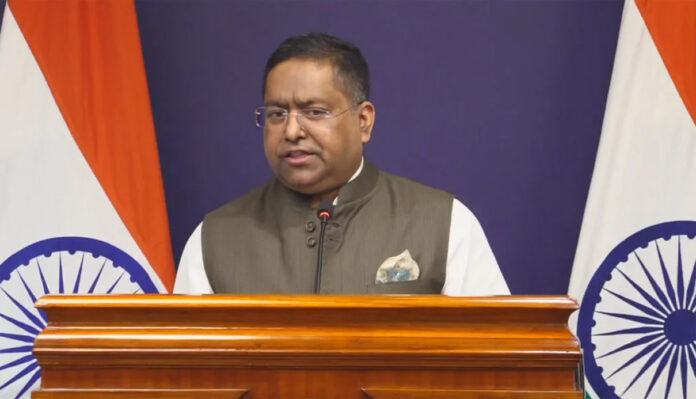 randhir-jaiswal-mea-briefin MEA spokesperson Randhir Jaiswal addressing press briefing on H-1B visa delays and overseas Indian citizens issues December 2025