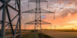 High-voltage electricity transmission tower in Indian countryside at sunset, illustrating power infrastructure growth for Adani Energy Solutions