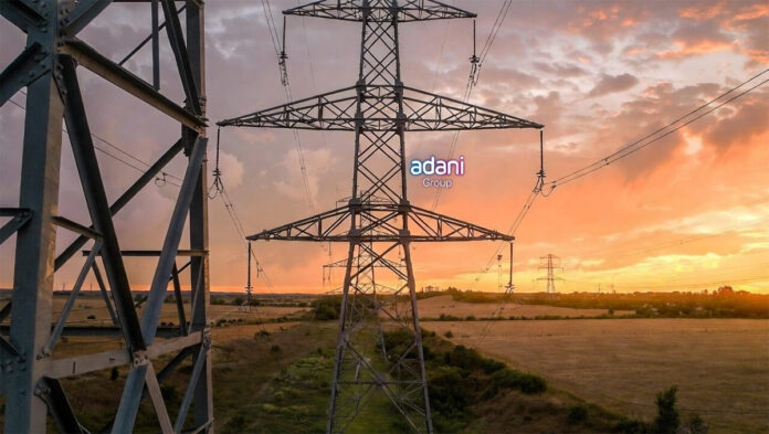 adani-energy-solutions-q3-f High-voltage electricity transmission tower in Indian countryside at sunset, illustrating power infrastructure growth for Adani Energy Solutions