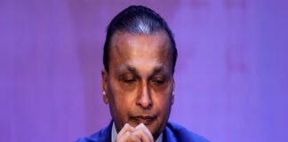 Anil Ambani during corporate event with overlay text indicating ED asset attachment January 2026