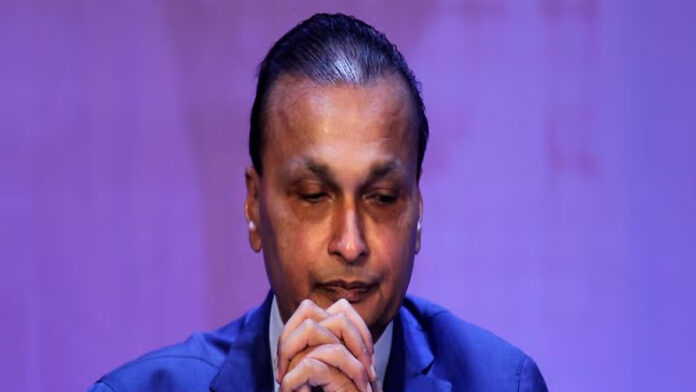 anil-ambani-reliance-adag-e Anil Ambani during corporate event with overlay text indicating ED asset attachment January 2026