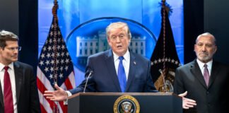 President Donald Trump speaking about tariffs and American trade policy as shipping containers sit at a US port