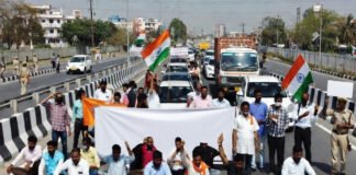Protesters holding banners during Bharat Bandh demonstration with blocked highway in India
