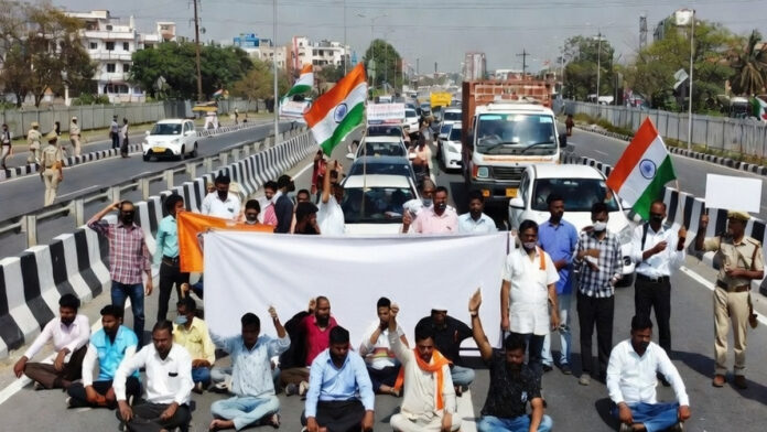 bharat-bandh-february-12-20 Protesters holding banners during Bharat Bandh demonstration with blocked highway in India