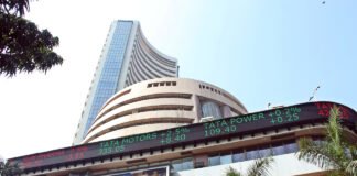 Bombay Stock Exchange building with green stock market numbers showing Sensex and Nifty gains