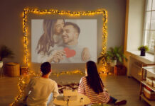 Valentine’s Weekend OTT Releases: From Courtroom Drama to Horror Thrillers, What to Stream Now Couple watching movies on OTT platforms during Valentine weekend with Netflix and ZEE5 visible on TV screen.