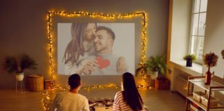 Couple watching movies on OTT platforms during Valentine weekend with Netflix and ZEE5 visible on TV screen.