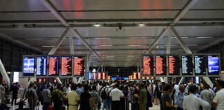 Passengers waiting at Dubai International Airport as Middle East crisis causes flight cancellations and ticket price surge