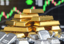 Gold Jumps Over ₹8,000, Silver Surges ₹23,000 Amid Iran Conflict Fears; Safe-Haven Buying Intensifies A close-up of gold bars and stacked silver bullion with a digital trading screen in the background showing rising price charts, symbolizing the sharp rally in precious metals.