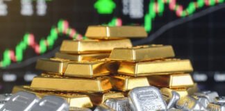 A close-up of gold bars and stacked silver bullion with a digital trading screen in the background showing rising price charts, symbolizing the sharp rally in precious metals.