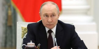 President Vladimir Putin overseeing Russian energy strategy meeting in Moscow March 2026 with charts showing Urals crude premium over Brent and Middle East conflict map