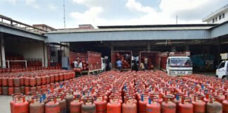 LPG gas cylinders stacked at distribution center in India with delivery staff preparing for supply