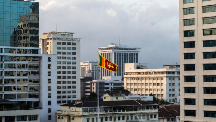 Sri-Lanka-Privatization-Pol Colombo skyline with government buildings and Sri Lankan flag representing economic policy decision