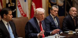 Donald Trump signing executive order on college sports reforms with documents and US flag